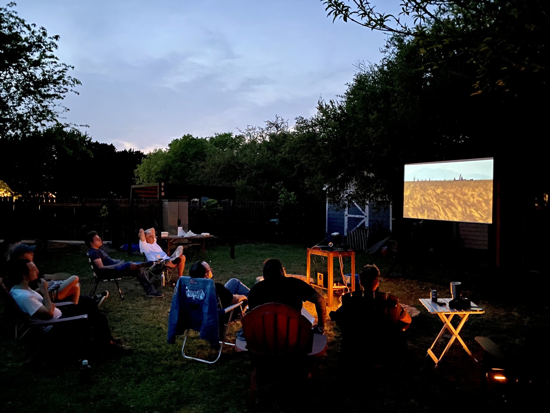 A group watching a backyard screening at dusk