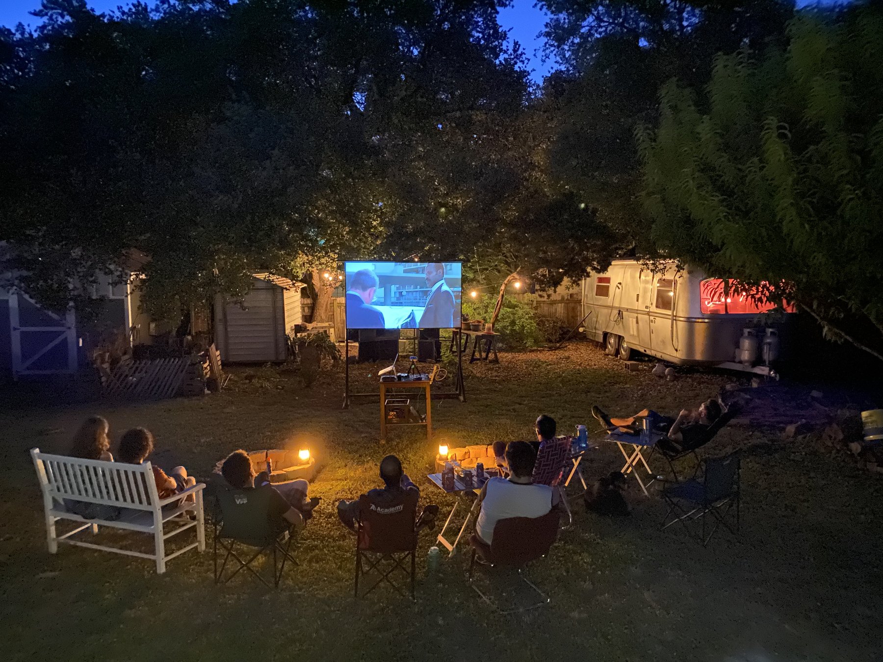 A group watching a backyard screening at night