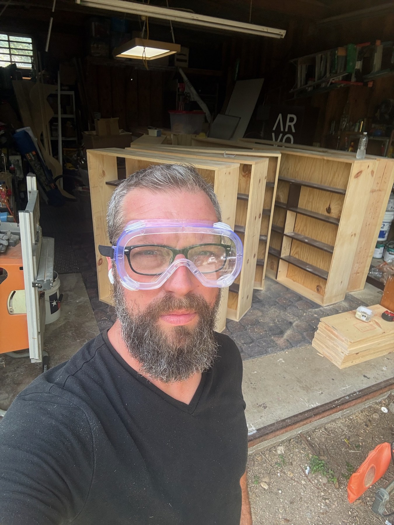 Beau Harris in safety goggles beside custom shelving in progress